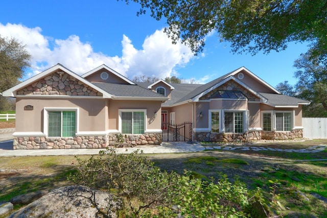 craftsman inspired home with a gate, stone siding, stucco siding, and fence