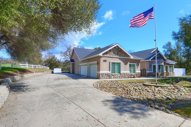 view of front of home featuring fence, stucco siding, concrete driveway, a garage, and stone siding