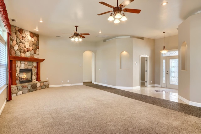 unfurnished living room with carpet flooring, arched walkways, baseboards, and a fireplace