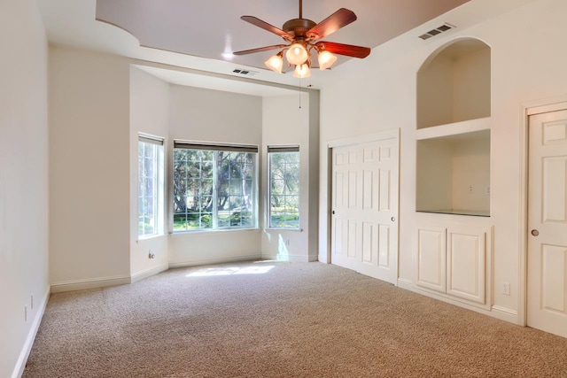 carpeted spare room featuring visible vents, baseboards, and ceiling fan