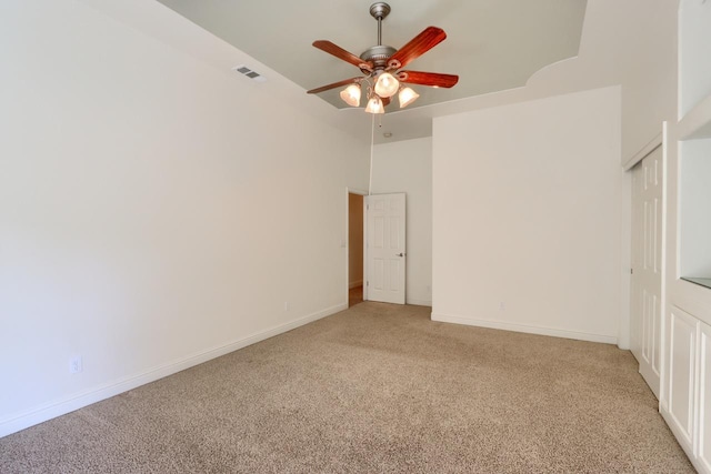 spare room featuring light carpet, visible vents, ceiling fan, and baseboards