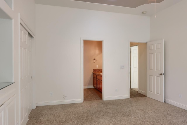 unfurnished bedroom with a closet, baseboards, carpet, and ensuite bathroom