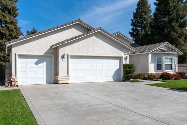 ranch-style house featuring a tile roof, an attached garage, driveway, and stucco siding