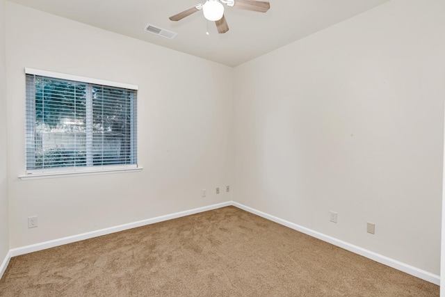 carpeted spare room with visible vents, baseboards, and a ceiling fan