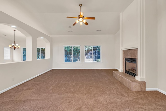 unfurnished living room with visible vents, a tile fireplace, dark colored carpet, baseboards, and vaulted ceiling