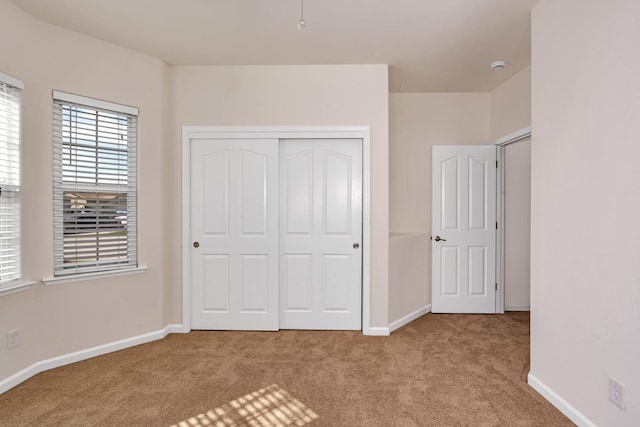 unfurnished bedroom featuring carpet, a closet, and baseboards