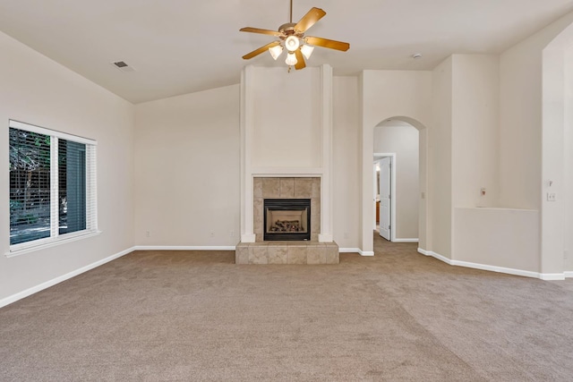 unfurnished living room with baseboards, visible vents, carpet floors, arched walkways, and a tile fireplace