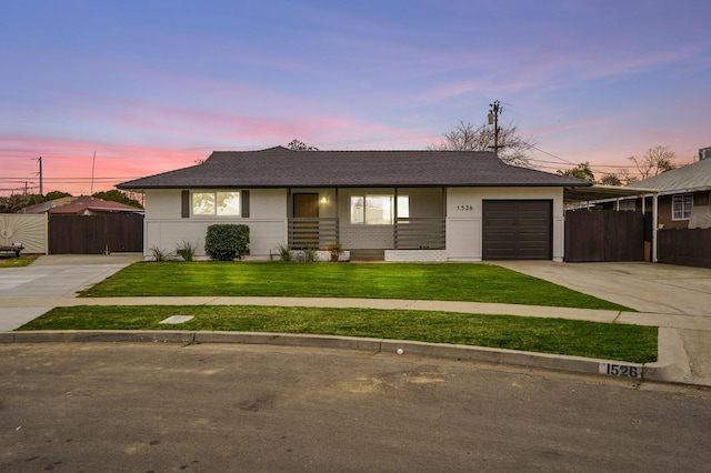 view of front of property with an attached garage, concrete driveway, a front lawn, and fence