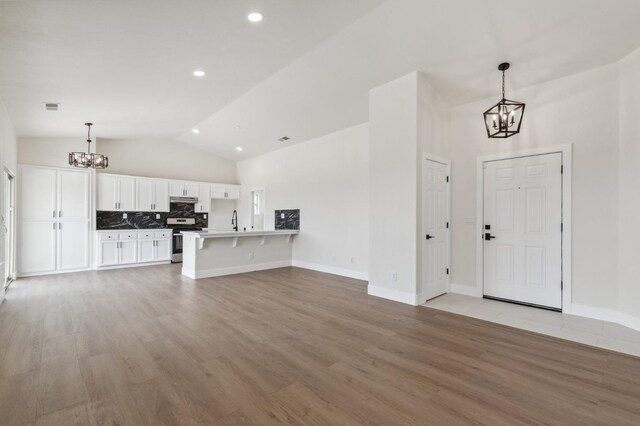 interior space featuring light wood-type flooring, baseboards, visible vents, and a chandelier