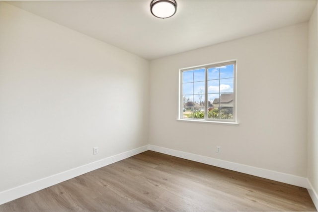 spare room with baseboards and wood finished floors