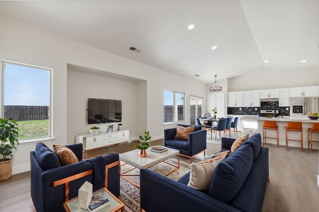 living area featuring light wood finished floors, visible vents, recessed lighting, and vaulted ceiling