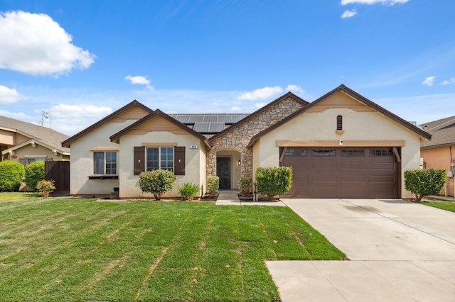 ranch-style house with stone siding, an attached garage, solar panels, and a front lawn