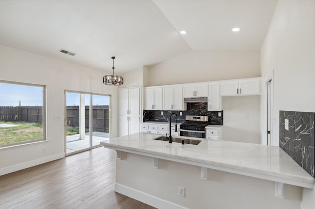 kitchen with light stone countertops, visible vents, a sink, vaulted ceiling, and tasteful backsplash