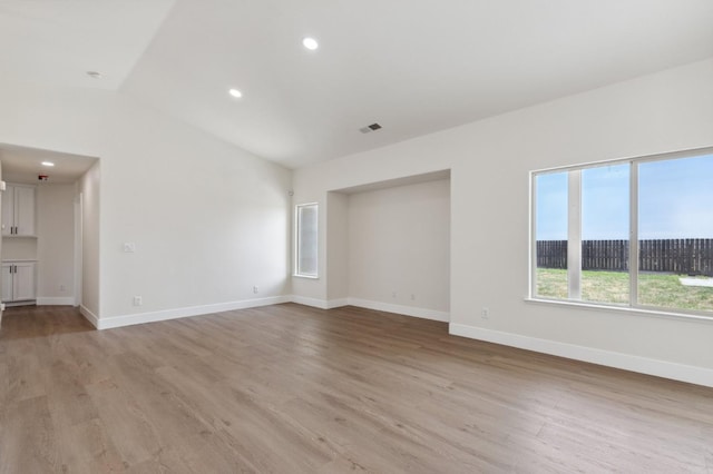 unfurnished living room featuring lofted ceiling, light wood-style flooring, baseboards, and visible vents