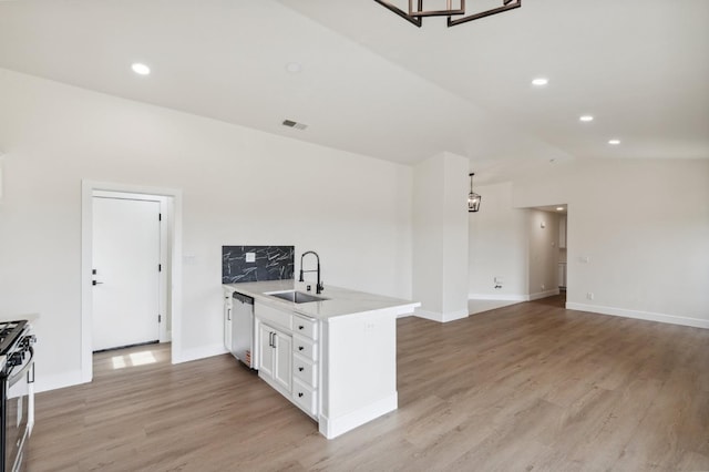 kitchen featuring light wood finished floors, appliances with stainless steel finishes, a peninsula, white cabinetry, and a sink