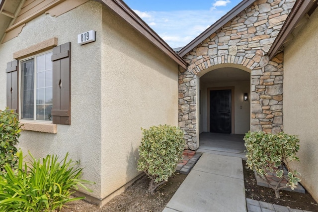 property entrance with stucco siding and stone siding