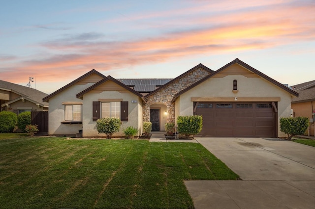 ranch-style house featuring stone siding, solar panels, an attached garage, and a front yard