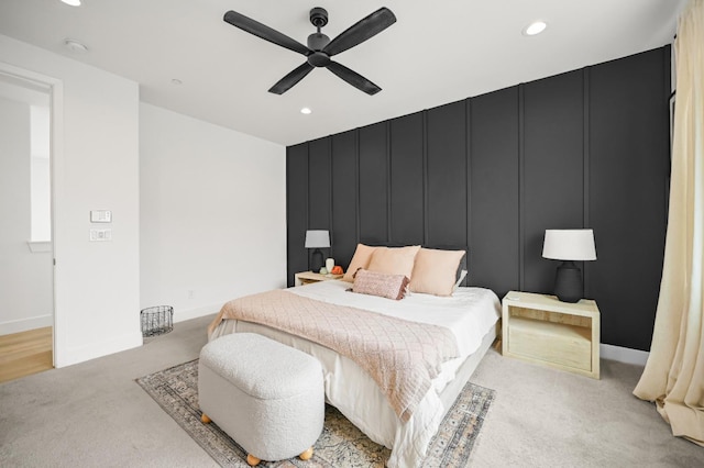 bedroom with baseboards, ceiling fan, light colored carpet, recessed lighting, and a decorative wall