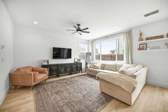 living room with light wood-style flooring, baseboards, visible vents, and ceiling fan