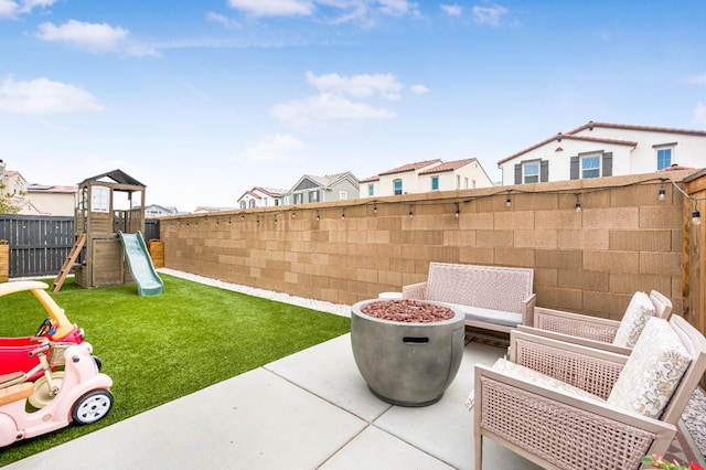 exterior space with a residential view, a playground, a fenced backyard, and an outdoor fire pit