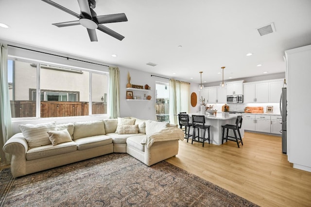 living room featuring recessed lighting, visible vents, light wood-style flooring, and a ceiling fan