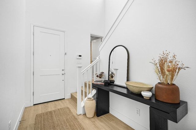 entrance foyer with stairs, baseboards, and light wood finished floors