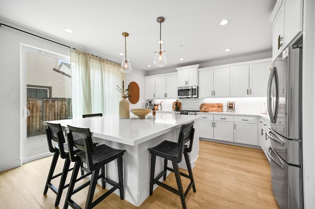 kitchen with light wood-type flooring, stainless steel appliances, white cabinets, and light countertops