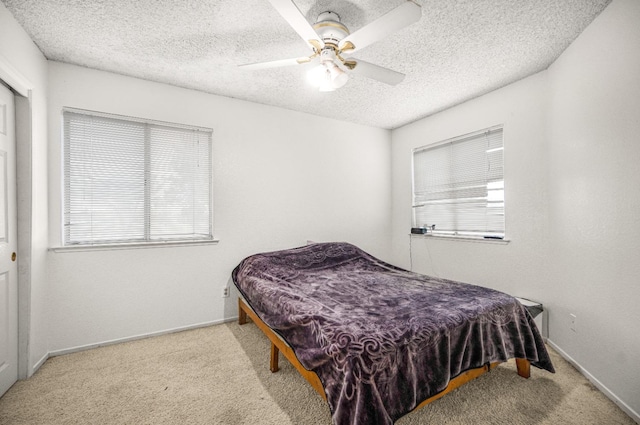 carpeted bedroom featuring baseboards, a textured ceiling, and ceiling fan