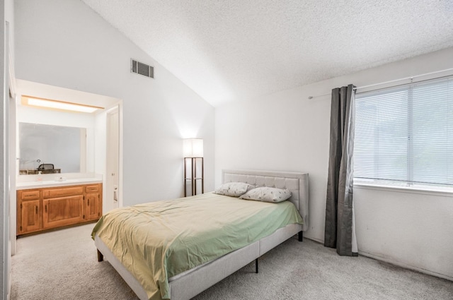 bedroom with visible vents, light colored carpet, a textured ceiling, and vaulted ceiling