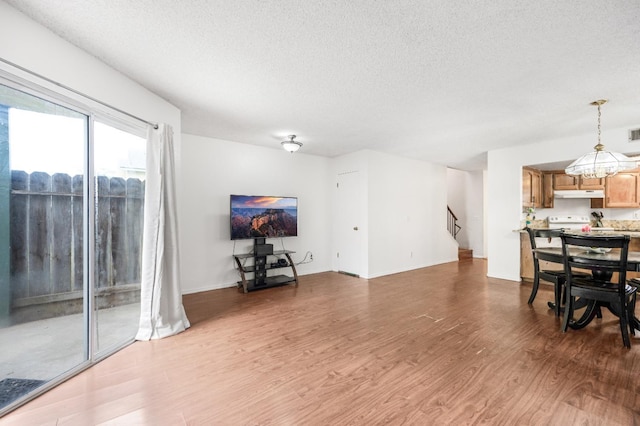 living room with stairway, wood finished floors, visible vents, and a textured ceiling