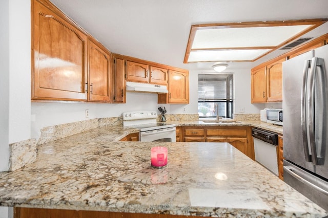 kitchen with white appliances, light stone counters, a peninsula, a sink, and under cabinet range hood