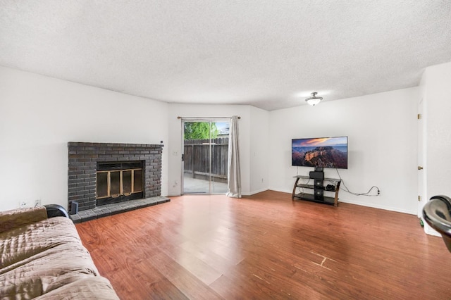 living room with baseboards, a textured ceiling, wood finished floors, and a fireplace