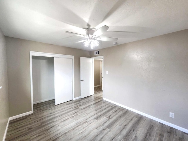 unfurnished bedroom with visible vents, wood finished floors, a closet, and baseboards