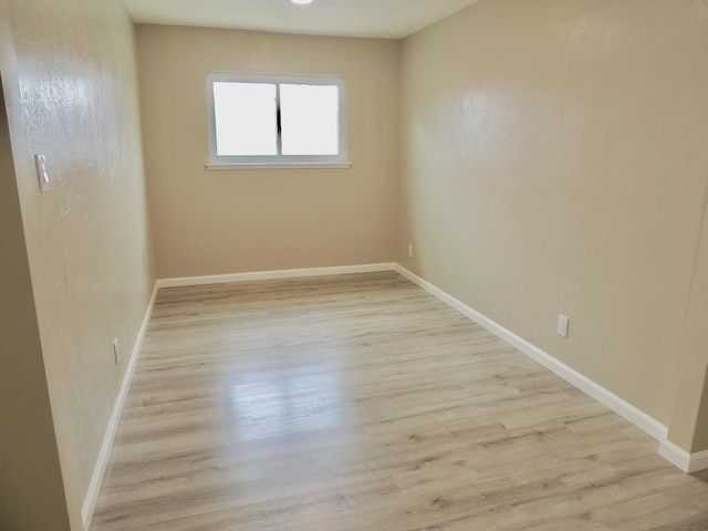 unfurnished room featuring baseboards and light wood finished floors