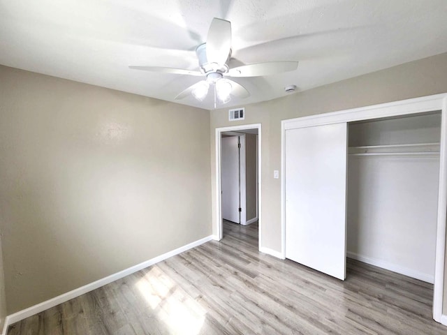 unfurnished bedroom with visible vents, wood finished floors, a closet, baseboards, and ceiling fan