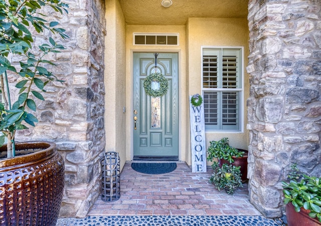 doorway to property featuring stone siding and stucco siding