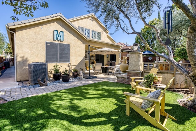 rear view of property with a yard, a patio area, central AC, and stucco siding