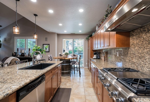 kitchen featuring under cabinet range hood, a wealth of natural light, brown cabinetry, stainless steel appliances, and a sink