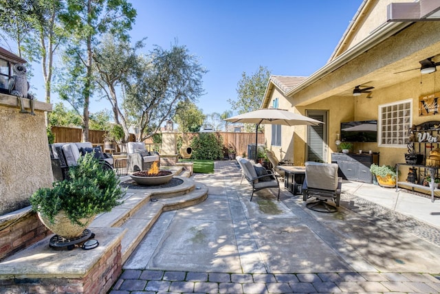 view of patio with fence, outdoor dining space, a ceiling fan, and an outdoor fire pit