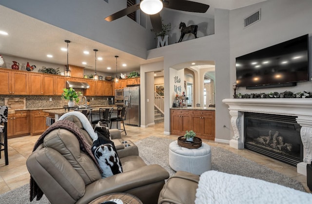 living room featuring visible vents, baseboards, ceiling fan, stairway, and a glass covered fireplace