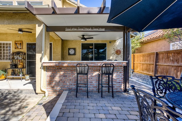 view of patio featuring fence, outdoor dry bar, and ceiling fan