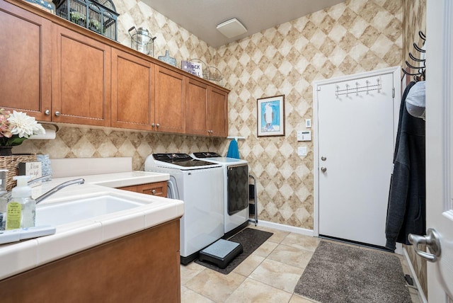 washroom featuring baseboards, washing machine and dryer, light tile patterned floors, cabinet space, and a sink