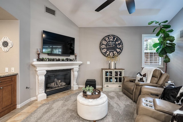 living room featuring visible vents, lofted ceiling, light tile patterned floors, a glass covered fireplace, and a ceiling fan