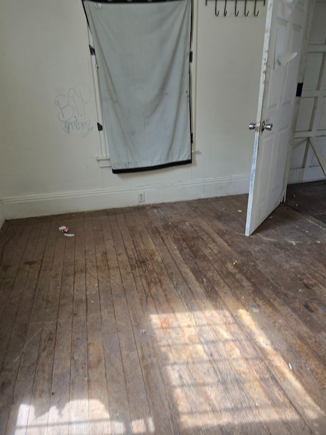 spare room featuring hardwood / wood-style flooring and baseboards