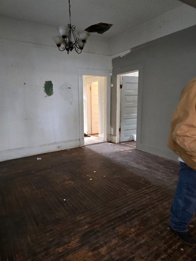 empty room with hardwood / wood-style floors and a chandelier