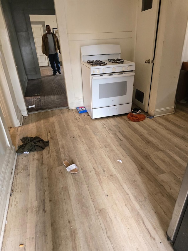 kitchen with white range with gas stovetop and light wood-style floors