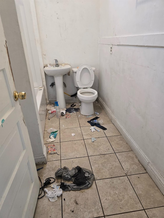 bathroom featuring tile patterned floors, toilet, baseboards, and a sink