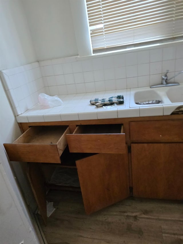 bathroom with a sink, backsplash, and wood finished floors