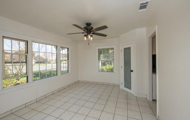 empty room featuring a wealth of natural light, visible vents, a ceiling fan, and light tile patterned floors