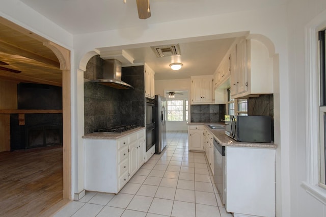 kitchen with visible vents, black appliances, a ceiling fan, and wall chimney range hood